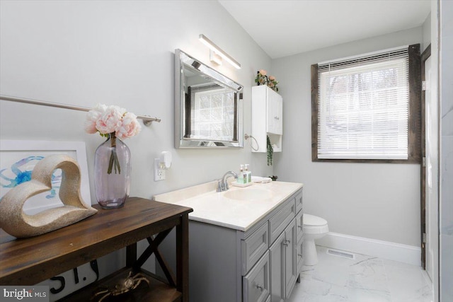 bathroom featuring visible vents, toilet, marble finish floor, baseboards, and vanity