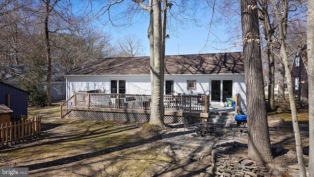 back of house with a wooden deck, roof with shingles, and fence