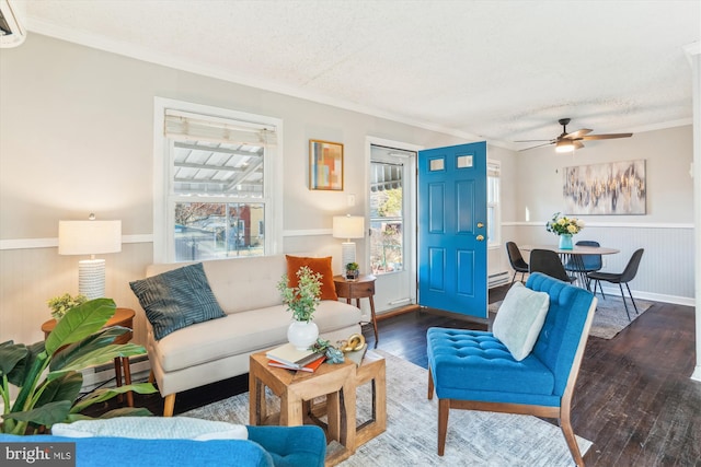 living area featuring ornamental molding, wood-type flooring, a wainscoted wall, and plenty of natural light