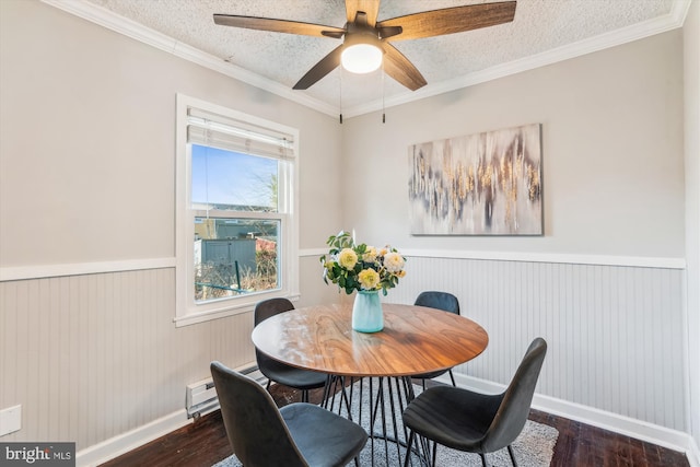 dining area with a textured ceiling, ornamental molding, a wainscoted wall, and dark wood finished floors