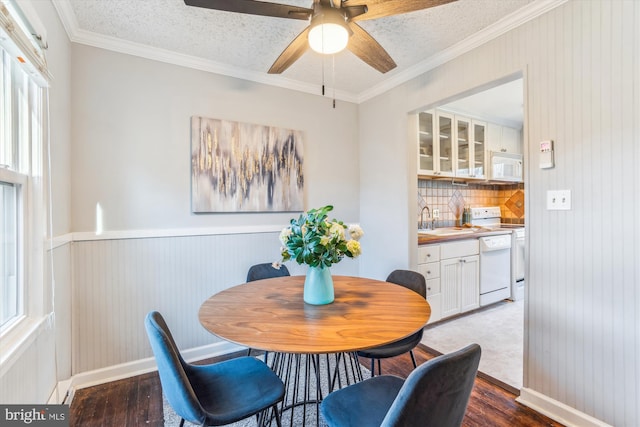 dining area with a textured ceiling, ornamental molding, wainscoting, and wood finished floors