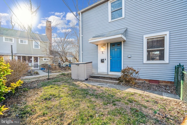 entrance to property featuring fence and a yard