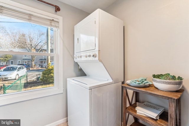 laundry room featuring laundry area, baseboards, and stacked washer / drying machine