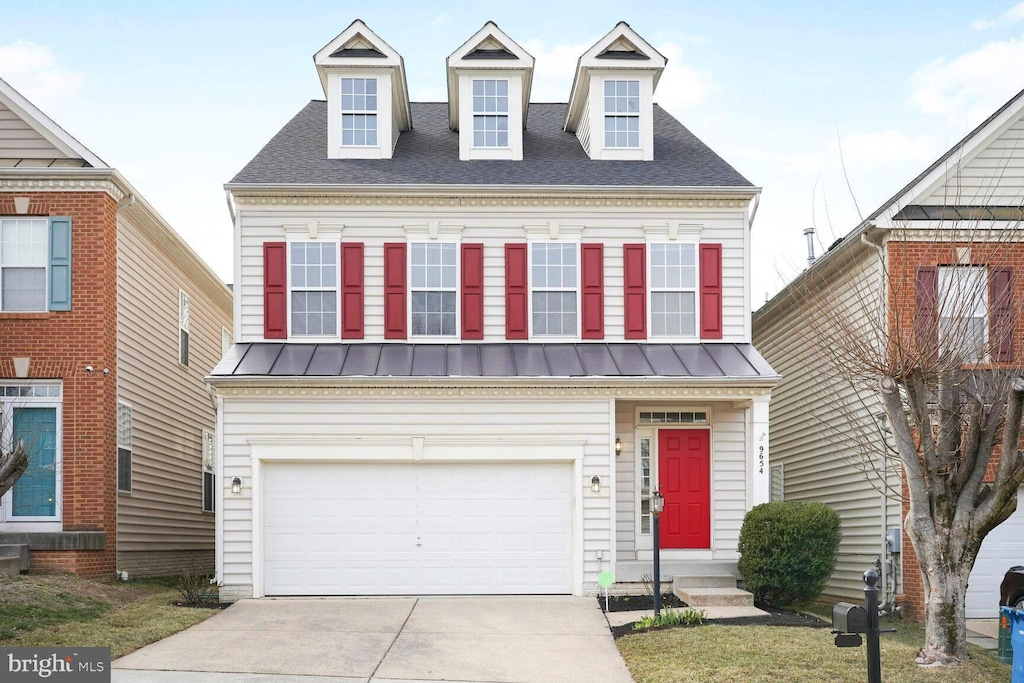 view of front facade with entry steps, a shingled roof, concrete driveway, metal roof, and a standing seam roof