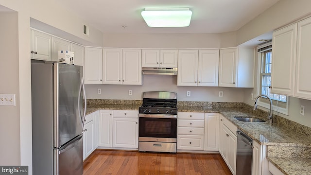 kitchen with visible vents, a sink, stainless steel appliances, under cabinet range hood, and light wood-type flooring