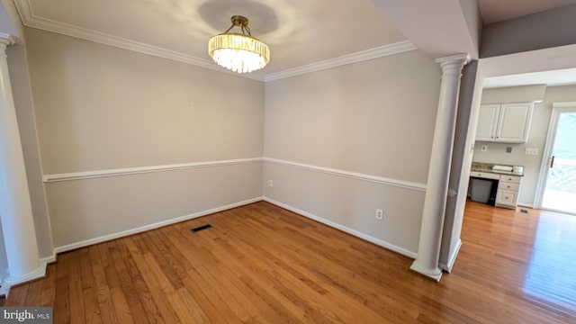 interior space featuring light wood-style flooring, ornamental molding, and decorative columns