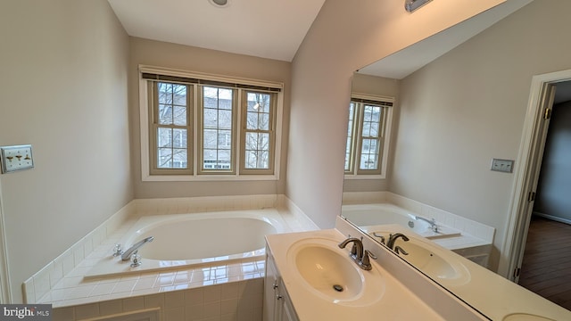 full bath featuring a bath, vanity, and vaulted ceiling