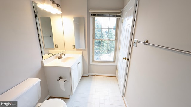 bathroom with toilet, vanity, and baseboards