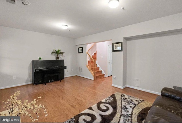 living area featuring visible vents, baseboards, wood finished floors, and stairs