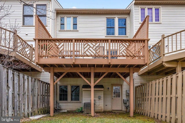 rear view of house with central AC unit, a wooden deck, and a fenced backyard