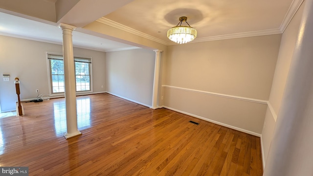 unfurnished room featuring decorative columns, visible vents, wood-type flooring, and ornamental molding