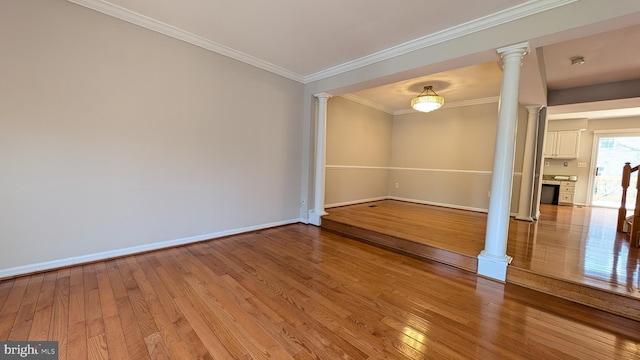 unfurnished room with hardwood / wood-style floors, decorative columns, baseboards, and ornamental molding