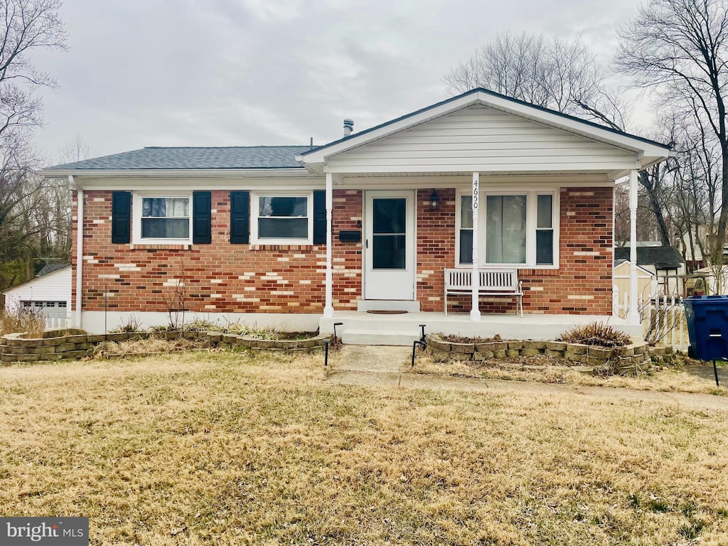 single story home with brick siding, a porch, a front yard, and roof with shingles