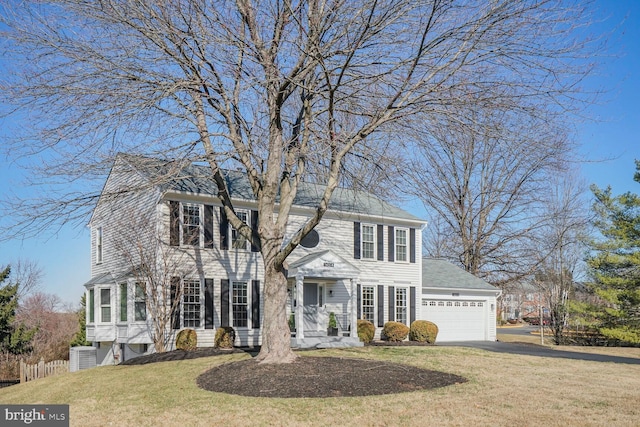 colonial home featuring driveway, a front yard, a garage, and fence