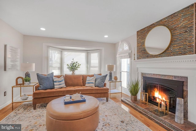 living area featuring light wood-type flooring, recessed lighting, baseboards, and a tile fireplace