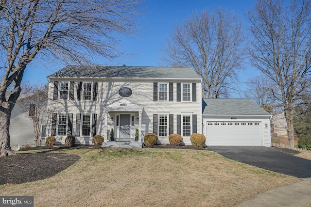 colonial house with aphalt driveway, an attached garage, and a front lawn