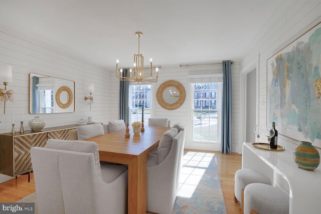 dining area with light wood-type flooring, a wealth of natural light, and an inviting chandelier