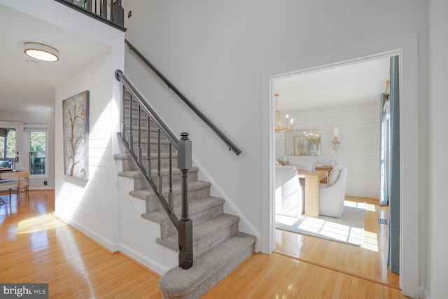 staircase featuring hardwood / wood-style flooring, baseboards, and a chandelier