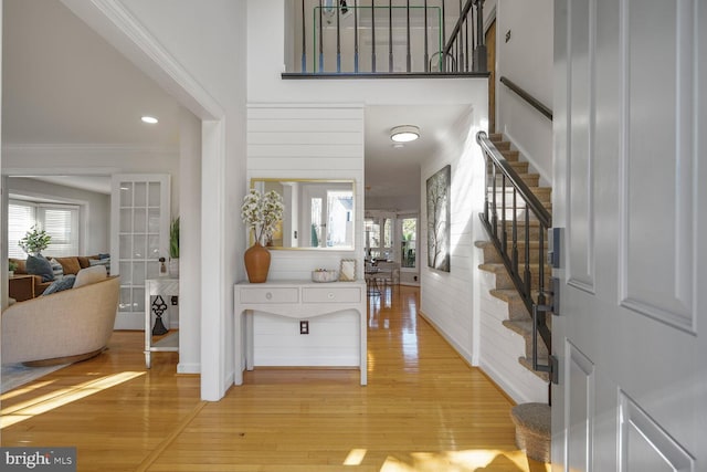 entrance foyer with a towering ceiling, light wood finished floors, and stairway