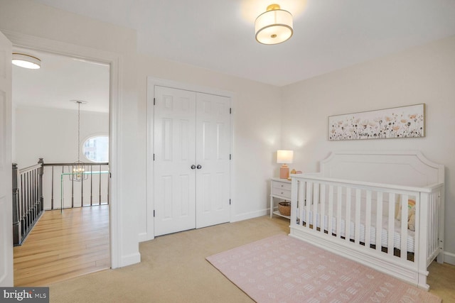 carpeted bedroom featuring a closet, an inviting chandelier, and baseboards