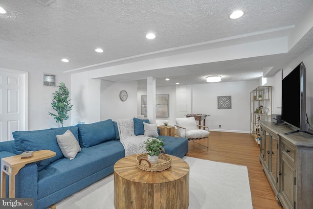 living area with a textured ceiling, baseboards, wood finished floors, and recessed lighting