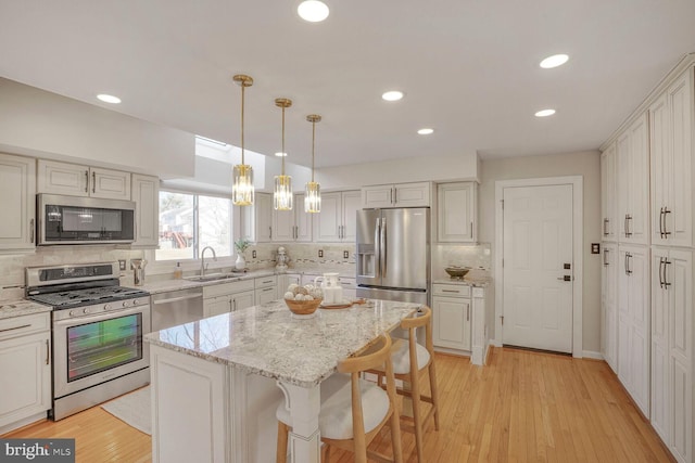 kitchen with light wood-style flooring, a kitchen bar, appliances with stainless steel finishes, and a sink