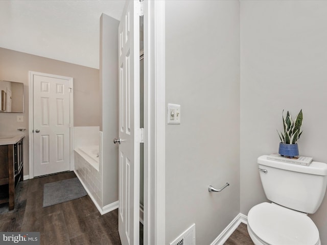 bathroom featuring visible vents, toilet, wood finished floors, baseboards, and a bath