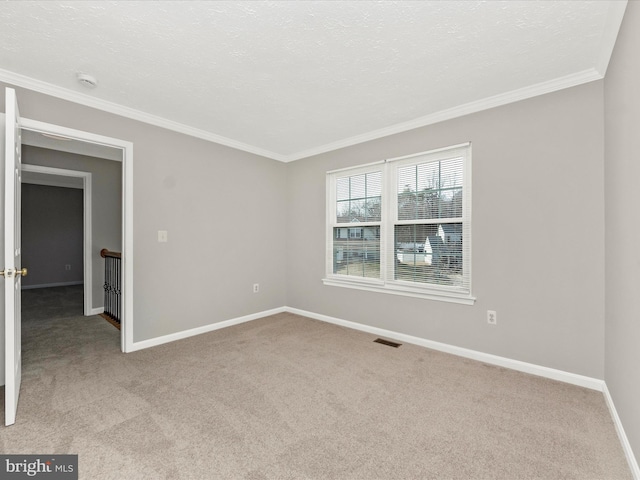 carpeted empty room with baseboards, a textured ceiling, and crown molding