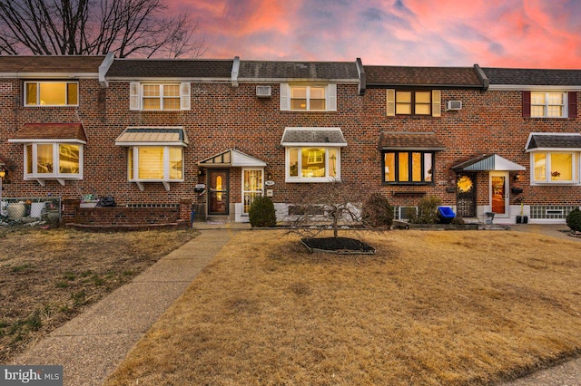 view of property featuring brick siding and a yard