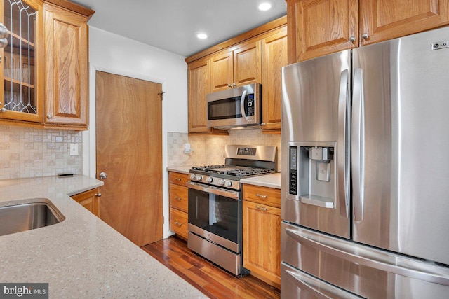 kitchen featuring tasteful backsplash, glass insert cabinets, appliances with stainless steel finishes, dark wood-style flooring, and recessed lighting