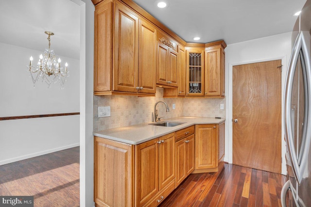 kitchen featuring dark wood-style floors, tasteful backsplash, light countertops, freestanding refrigerator, and a sink