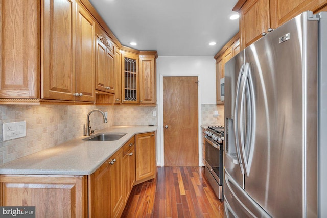 kitchen with dark wood-style flooring, stainless steel appliances, light countertops, glass insert cabinets, and a sink