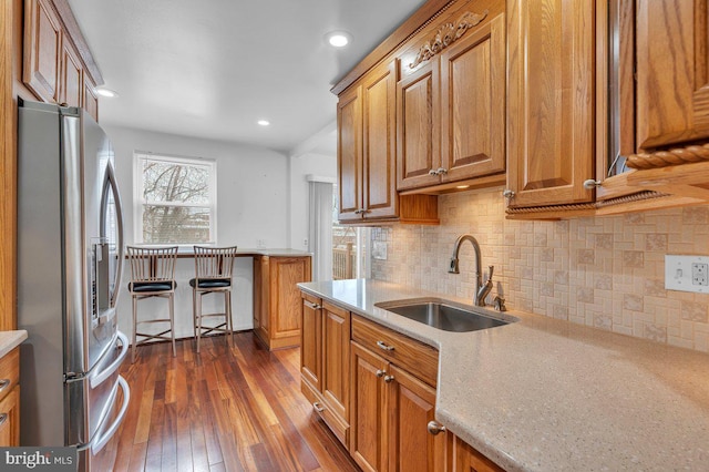 kitchen with light countertops, brown cabinets, a sink, and stainless steel fridge with ice dispenser