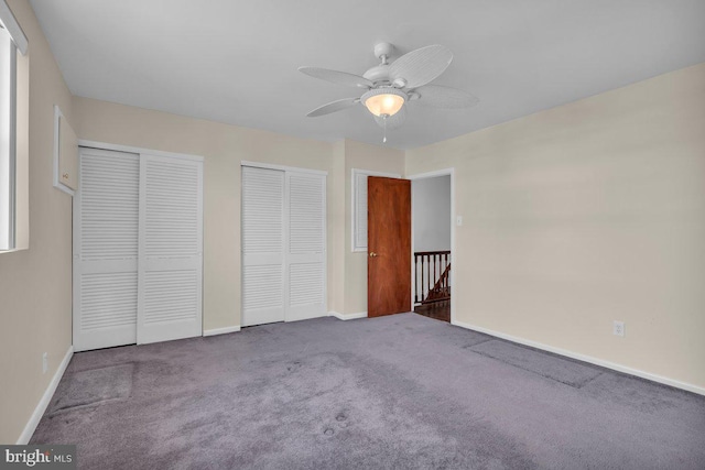 unfurnished bedroom featuring carpet floors, a ceiling fan, baseboards, and multiple closets