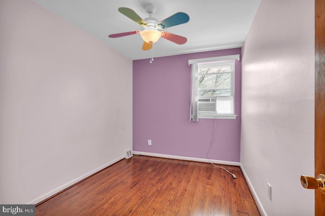 empty room with a ceiling fan, cooling unit, baseboards, and wood finished floors