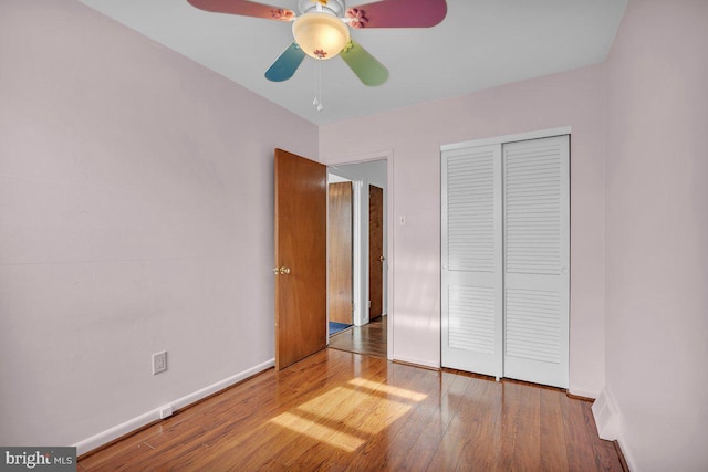 unfurnished bedroom with a closet, wood finished floors, and baseboards