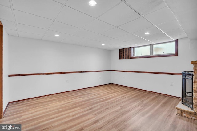 below grade area with light wood-type flooring, baseboards, a drop ceiling, and recessed lighting