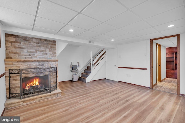 unfurnished living room featuring recessed lighting, a fireplace, baseboards, stairs, and light wood finished floors