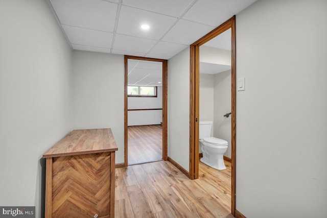 bathroom featuring baseboards, a drop ceiling, toilet, and wood finished floors