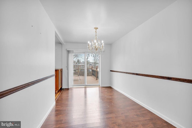 unfurnished dining area with baseboards, a chandelier, and wood finished floors