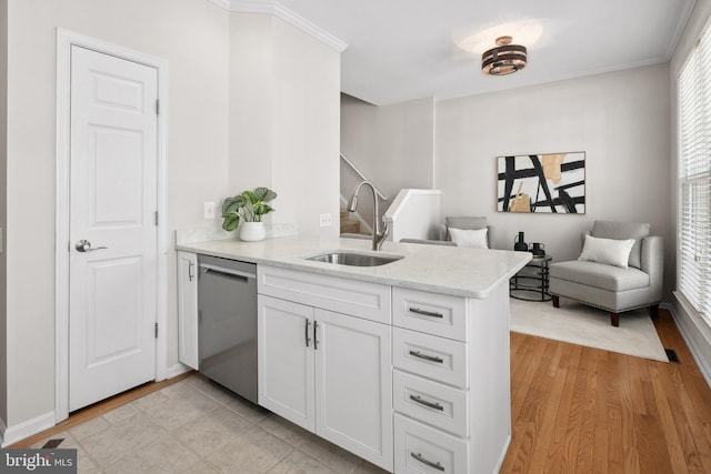 kitchen featuring a peninsula, stainless steel dishwasher, plenty of natural light, white cabinetry, and a sink