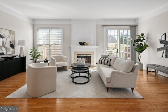 living room with a glass covered fireplace, light wood-style flooring, plenty of natural light, and ornamental molding