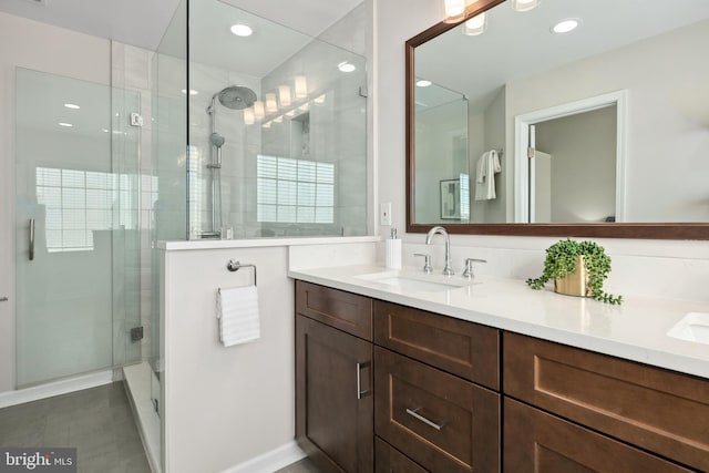 full bathroom with a shower stall, recessed lighting, double vanity, and a sink