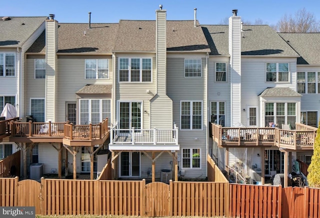 rear view of house with a fenced front yard, central AC unit, a chimney, and a gate