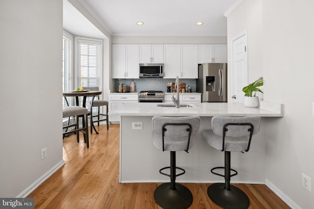 kitchen with a sink, white cabinets, backsplash, and stainless steel appliances