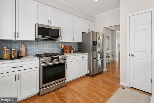 kitchen with stainless steel appliances, white cabinetry, ornamental molding, and light countertops