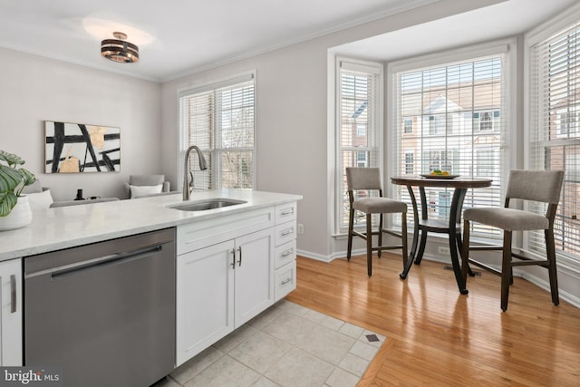 kitchen with a sink, light wood-style floors, white cabinets, crown molding, and dishwasher