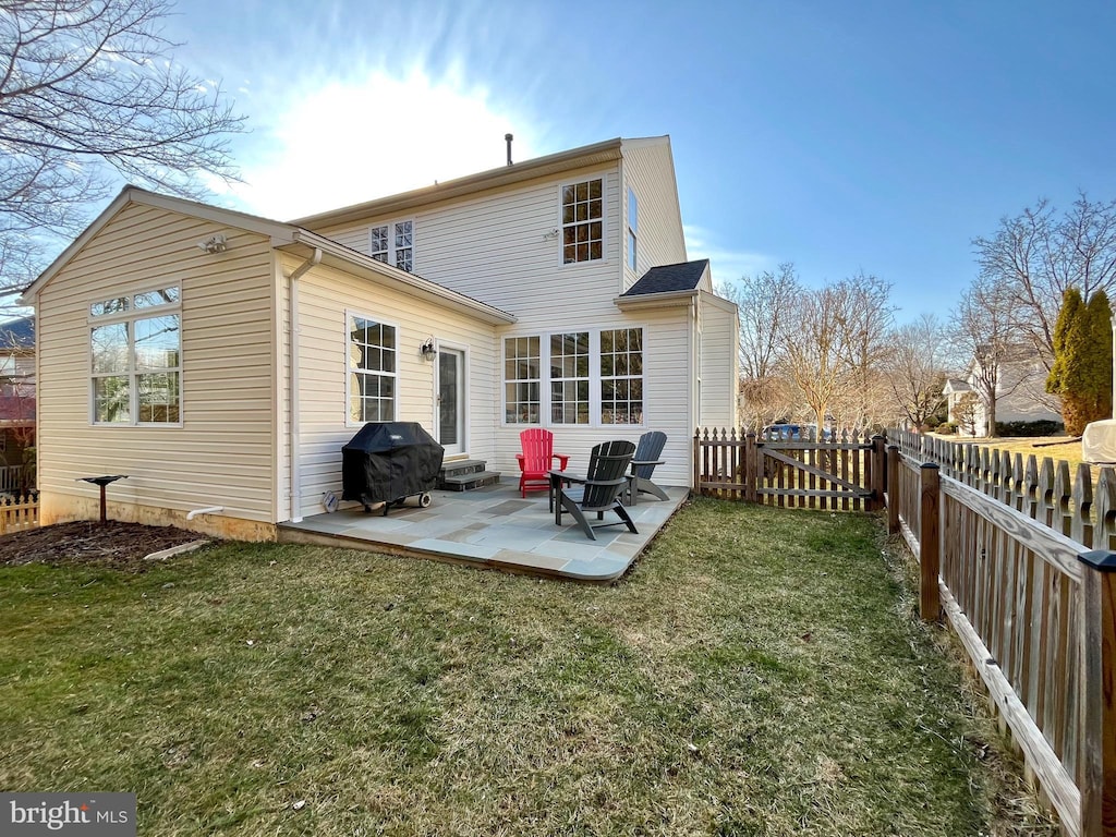 back of property with entry steps, a lawn, a patio area, and a fenced backyard