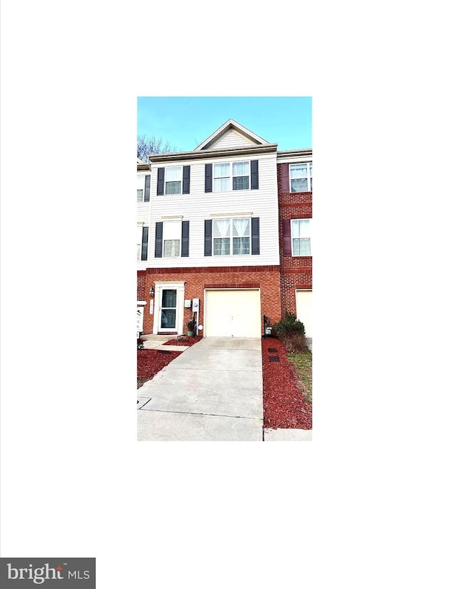 view of property featuring an attached garage, brick siding, and driveway