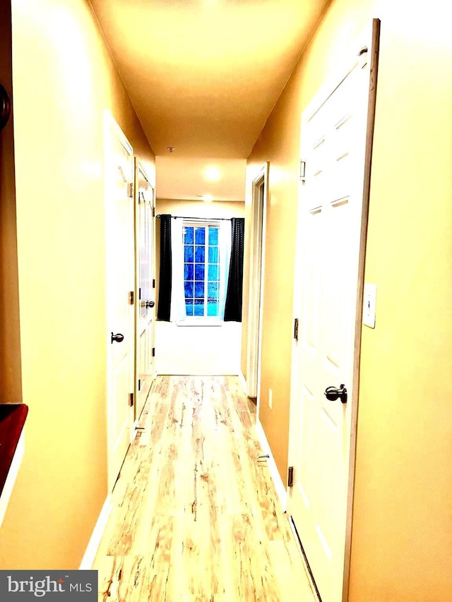 hall with light wood-style flooring and baseboards